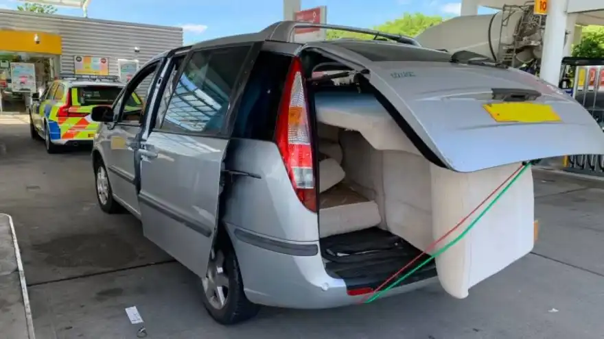Car driving with two unsecured sofas hanging out of the rear, and side, pulled over by police on the motorway